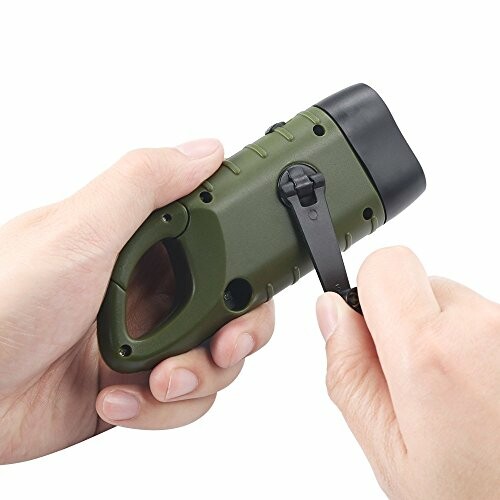 Hand holding a green hand-crank flashlight