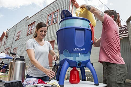 Two people setting up a large blue water filter outdoors.