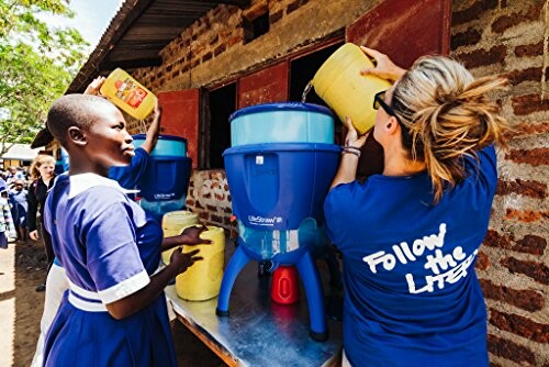 People demonstrating water filtration using a large blue filter.